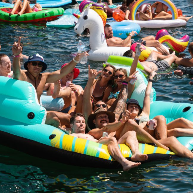 A group of people enjoying a day on the water is seated on an inflatable unicorn and other floats, with others swimming and relaxing nearby. Perfect for corporate boat events in Sydney or luxury yacht hire, it's an ideal way to experience a memorable Sydney boat party.