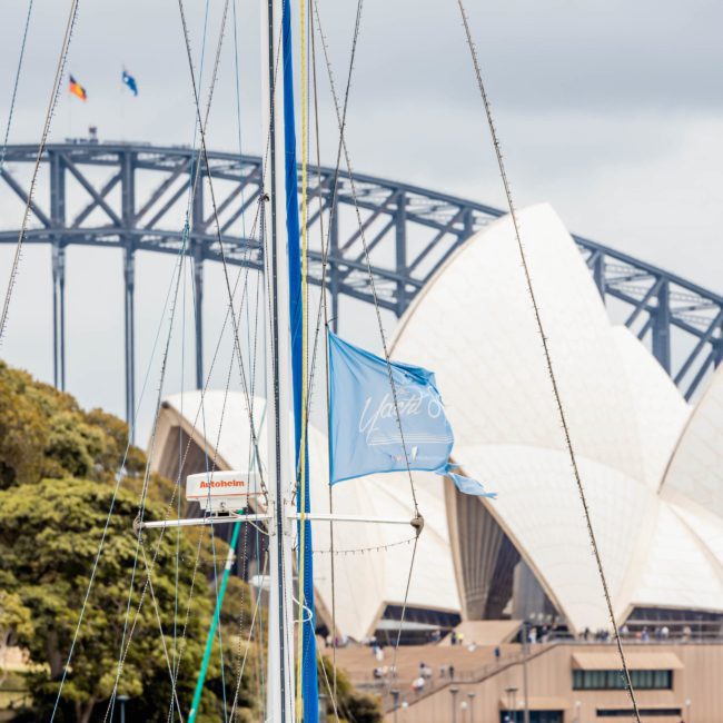 Enjoy a stunning view of sailboats in the foreground with the Sydney Opera House and Sydney Harbour Bridge in the background, perfect for a luxury yacht hire Sydney experience.