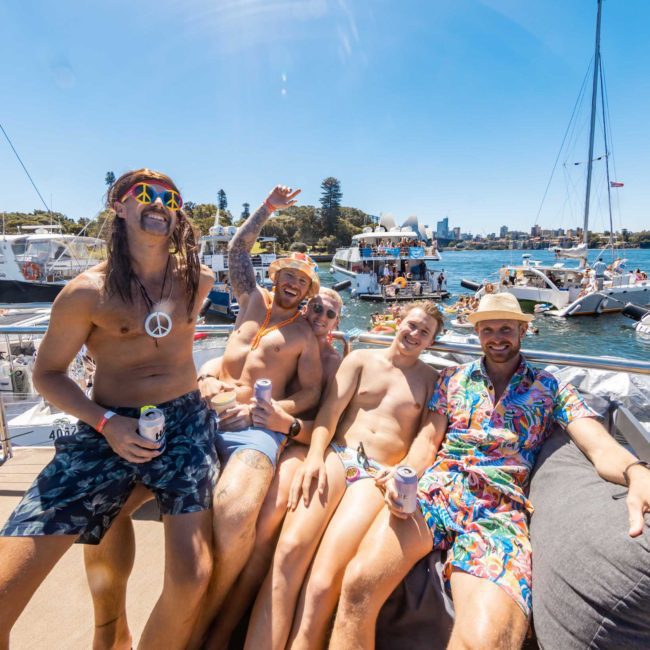 A group of people in swimwear and summer attire are sitting on a luxury yacht, surrounded by other boats on the water, smiling and enjoying a sunny day.