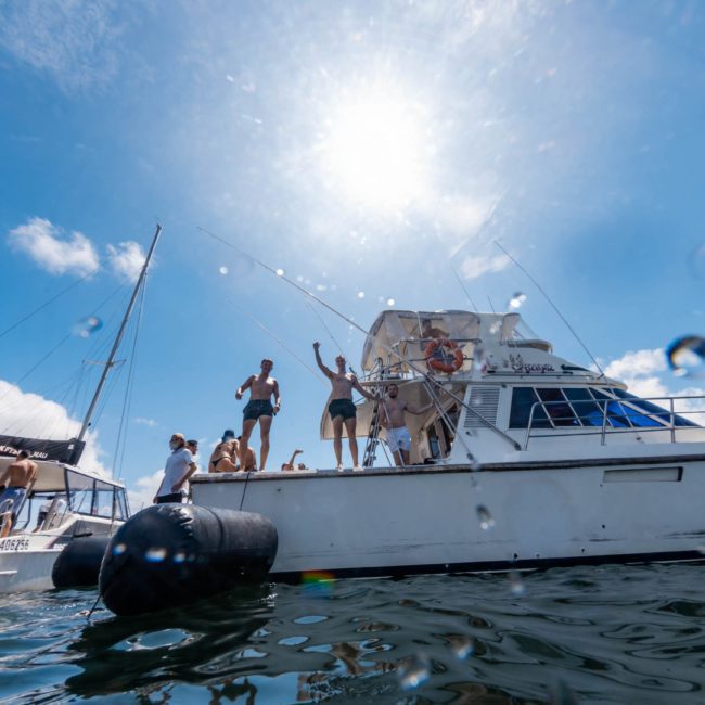 People enjoying themselves on a boat under a bright sun with another boat nearby on a sunny day, perfect for a Sydney boat party hire.