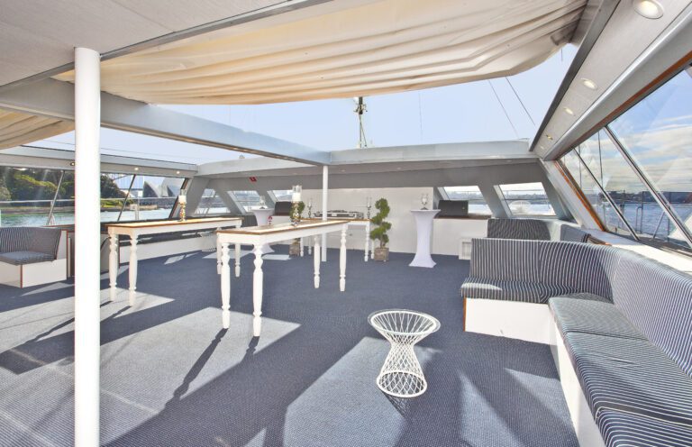 Aussie Magic’s spacious interior features striped seating, white tables, and large windows with stunning water and cityscape views, filling the area with natural light for an open, airy feel.