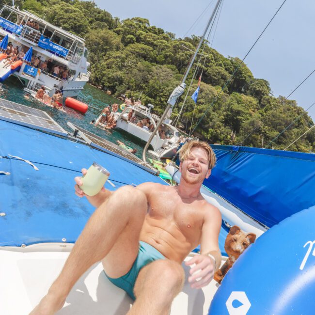 A man in a swimsuit on a boat with a dog.